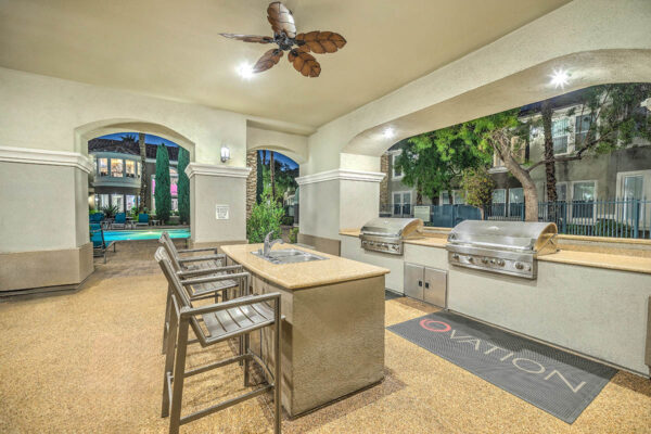 Indoor/outdoor lounge with built in BBQ grills, built in dining bar, and ceiling fan.