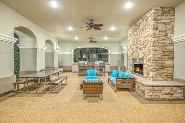 Indoor/outdoor lounge with built in BBQ grills, picnic table, couch, and fireplace.