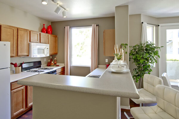 Kitchen with light wood cabinets, white counter bar, and track lighting.