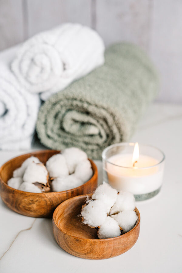 Spa table with flowers, glowing candle, and soft rolled towels.
