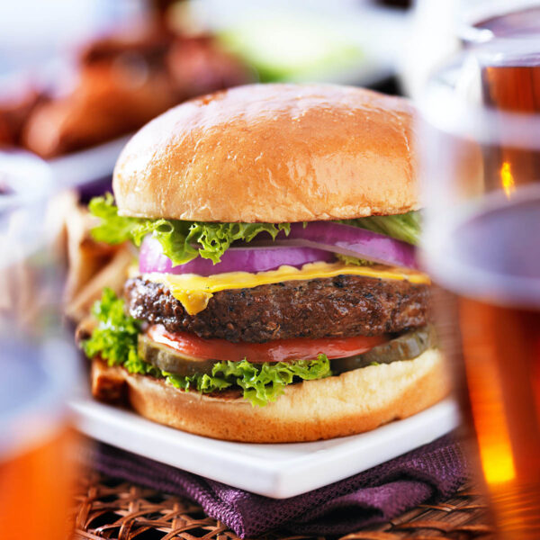 Cheeseburger on plate next to glasses of beer.