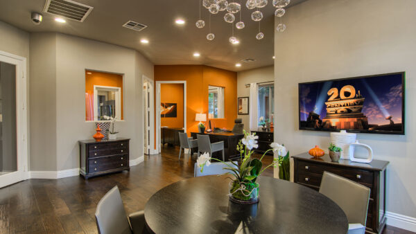 Leasing center with wood floor, tables with chairs, cabinet with decor, and TV.