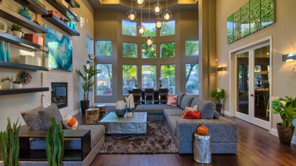Clubhouse with plush seating, large fireplace, shelves with decor, and two story windows.