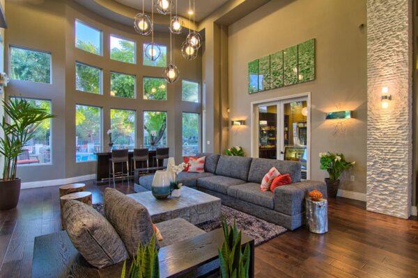 Clubhouse with plush seating, large artwork, tables with decor, and two story windows.