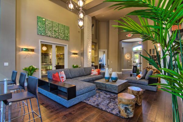 Clubhouse with plush seating, large artwork, tables with decor, and two story windows.