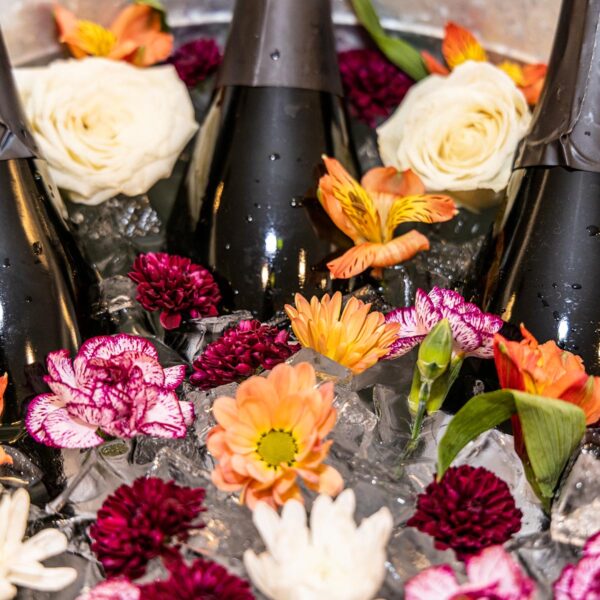 Champagne cooler with bottles, ice and flowers.