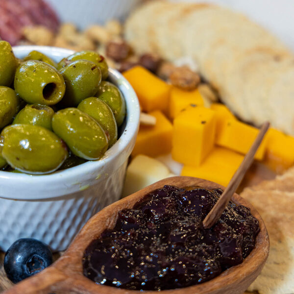 Charcuterie tray with crackers, cheese, jam, and olives.