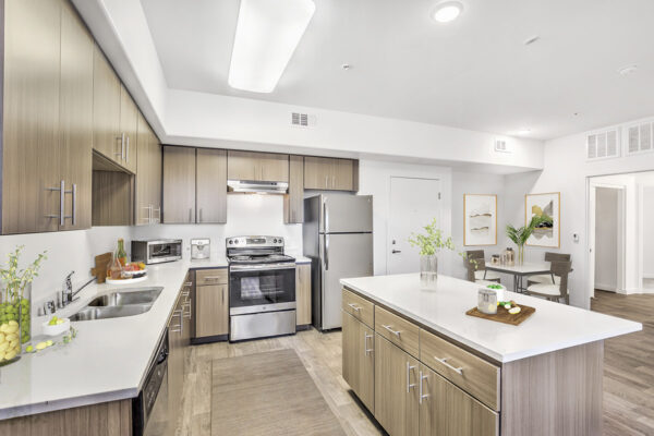 Kitchen with wood style floor, wood cabinets, light counters, and stainless steel appliances.