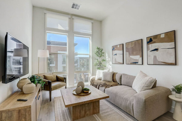Apartment living room with plush couch, wall mounted TV, and framed artwork.