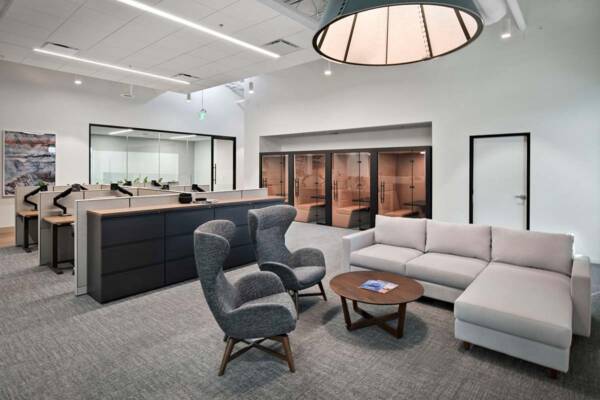 Office with plush seating, cubicles with desks, and small phone booths.