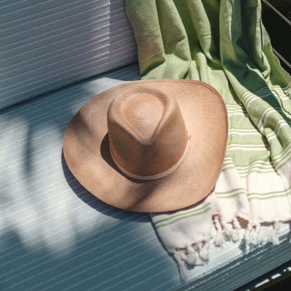 Outdoor chair with woven blanket and sun hat.