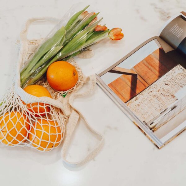 Marble table with photography book and produce bag with oranges and flowers.