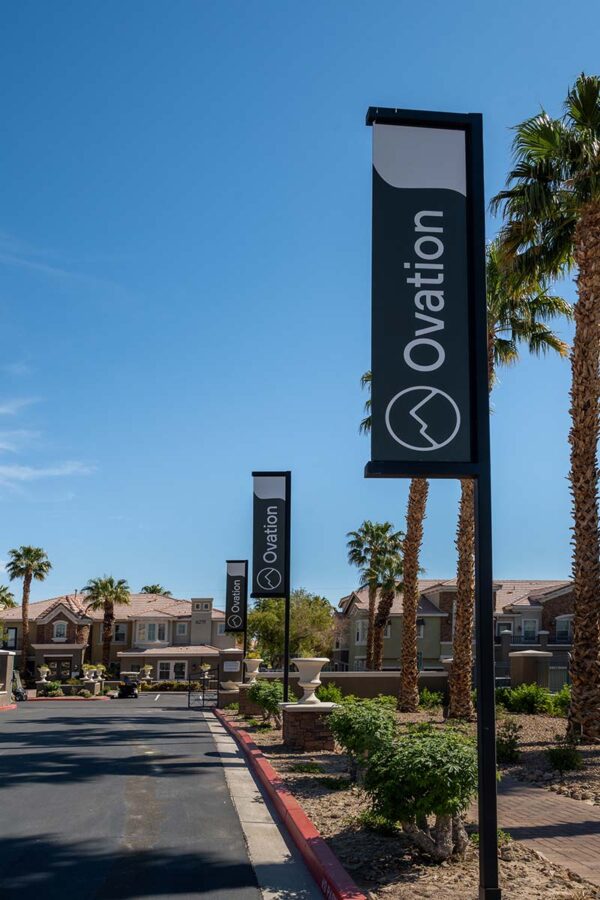 Arzano apartments entrance with rocky landscaping and palm trees.