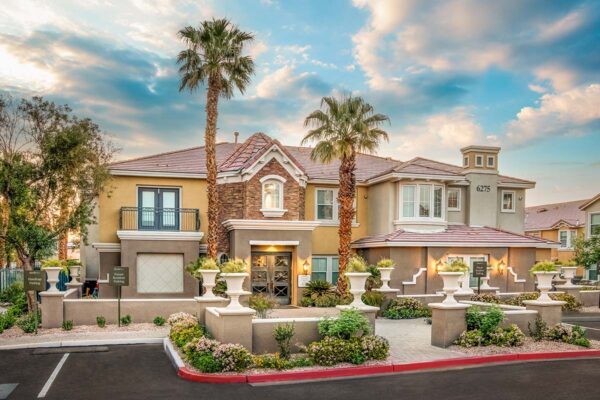 Arzano apartments clubhouse with lush landscaping and tall palm trees.