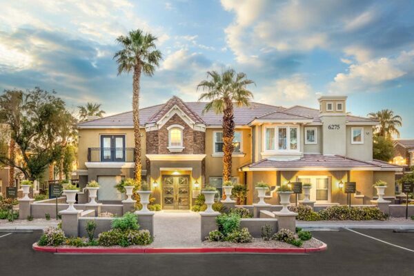 Arzano apartments clubhouse with lush landscaping and tall palm trees.