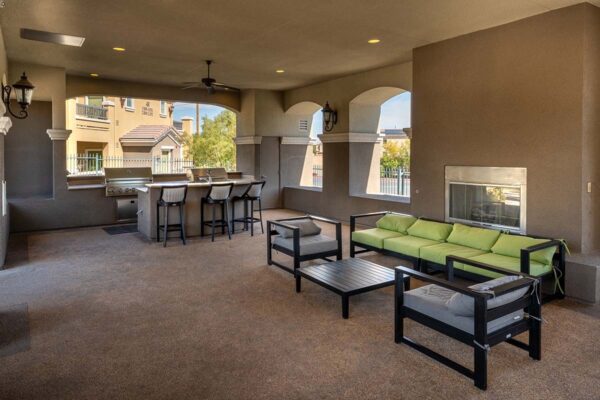 Arzano apartments outdoor lounge with fireplace, plush seating, and BBQ grill.