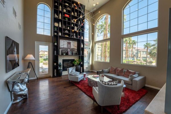 Arzano apartments clubhouse with plush seating, fireplace, shelves with decor, and large windows.