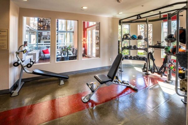 Arzano apartments fitness center with weight equipment and large windows.