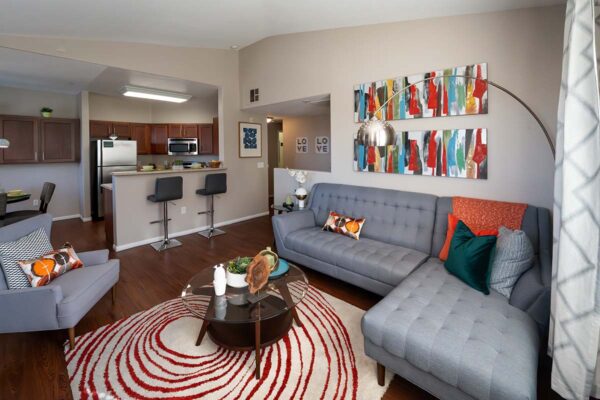 Arzano apartment living room with pattern rug, plush sectional, artwork, and floor standing lamp.