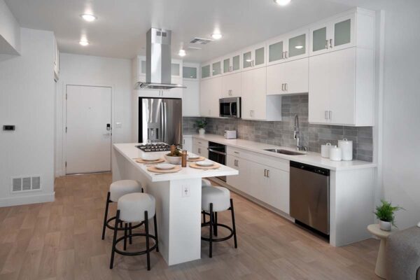Arzano apartment kitchen with wood style floor, white cabinets, tiled backsplash, and stainless steel appliances.