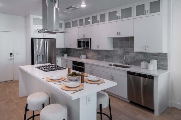 Arzano apartment kitchen with wood style floor, white cabinets and counters, and stainless steel appliances.