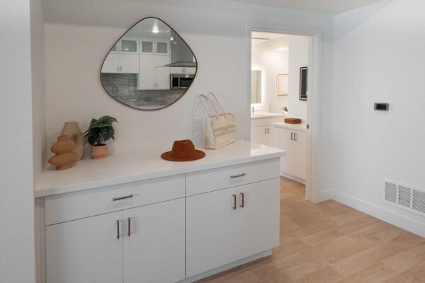 Arzano apartment kitchen storage area with built in cabinets and large mirror.