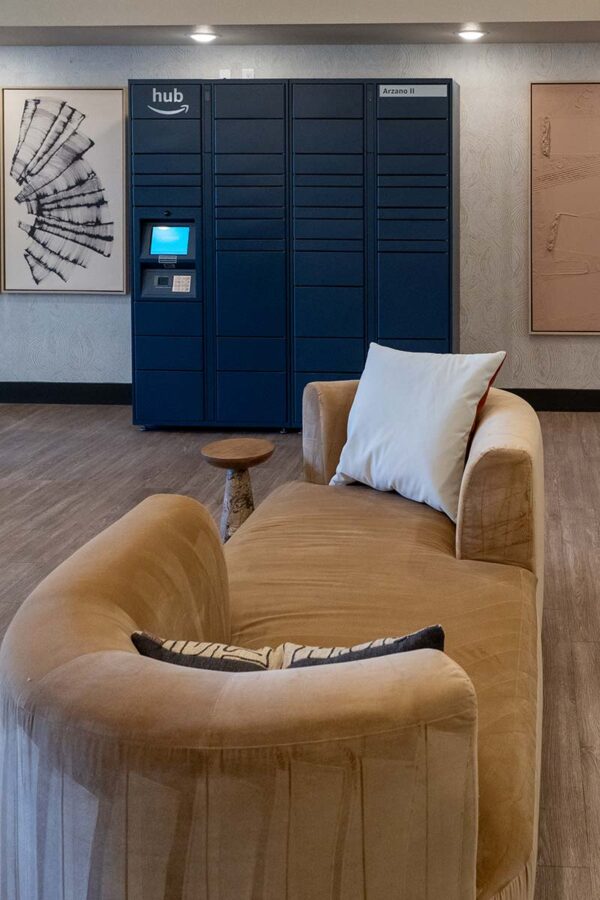 Arzano apartments mail room with plush couch and parcel locker.