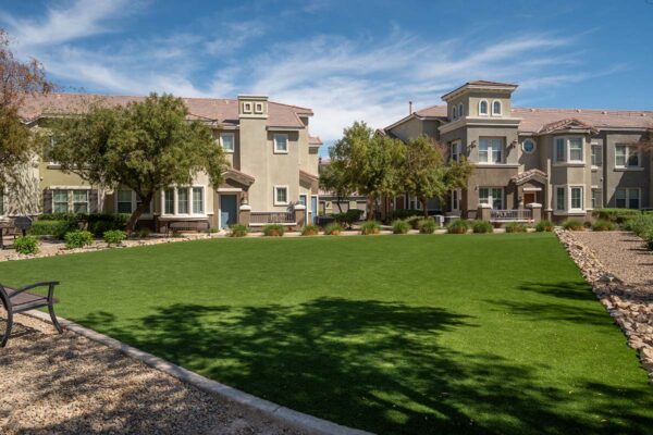 Arzano apartments common area with lush green lawn and benches.