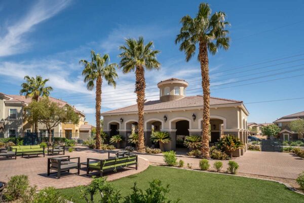 Arzano apartments outdoor lounge with plush seating, green lawns, and tall palm trees.