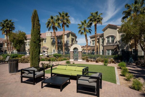 Arzano apartments with plush seating, lush landscaping, and tall trees.