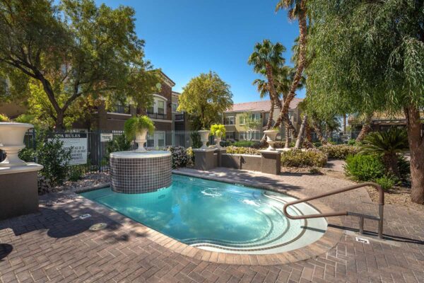 Arzano apartments pool area with spa and lush trees.