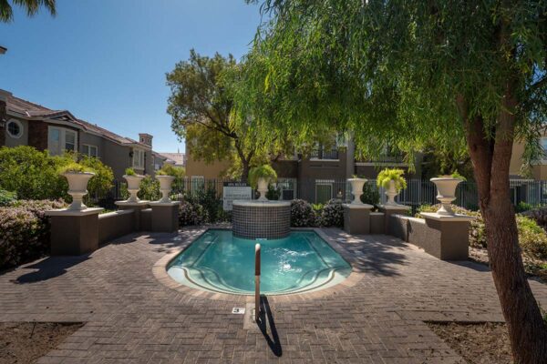 Arzano apartments pool area with spa and lush trees.