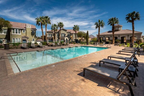 Arzano apartments pool area with lounge chairs and palm trees.
